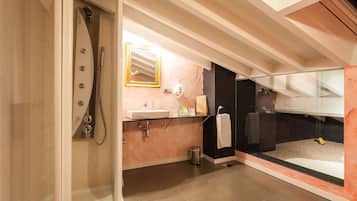 Un baño moderno con cabina de ducha de vidrio, un lavabo con espejo encima y una bañera negra visible a través de una mampara de cristal.