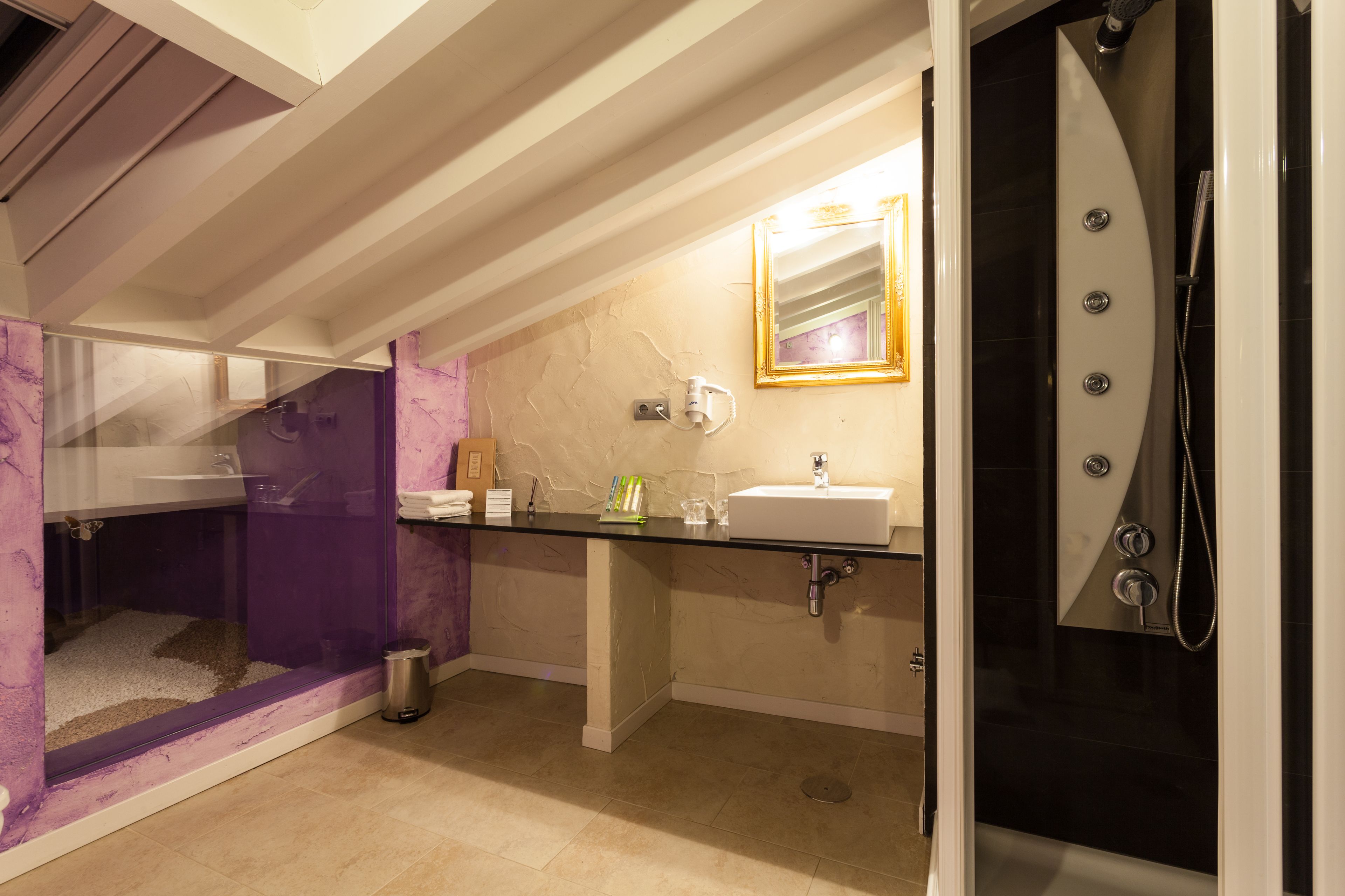 A modern bathroom with a glass-enclosed shower, a vanity with a sink, and a mirror with a gold frame.