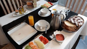 A breakfast buffet with various fruits, bread, and beverages.