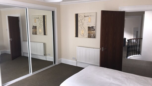 Ein Hotelzimmer mit einem Bett, einem großen Spiegel, einer Heizung und Kunstwerken an den Wänden.