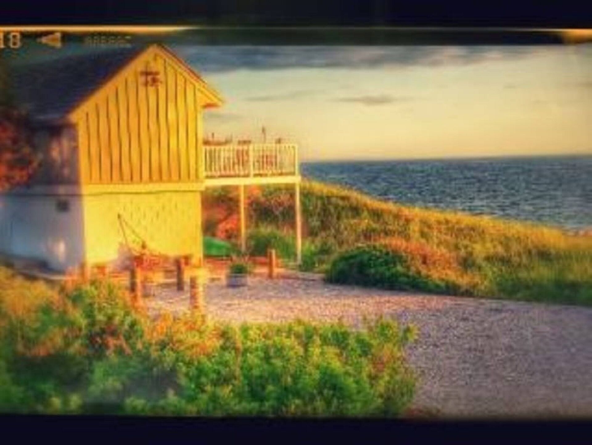 A wooden building with a porch, situated near a body of water.
