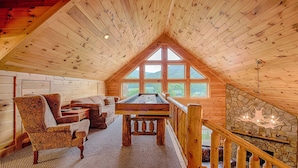 Une charmante cabane en bois avec une chambre à coucher aménagée en mezzanine, un coin repas et une cheminée en pierre.