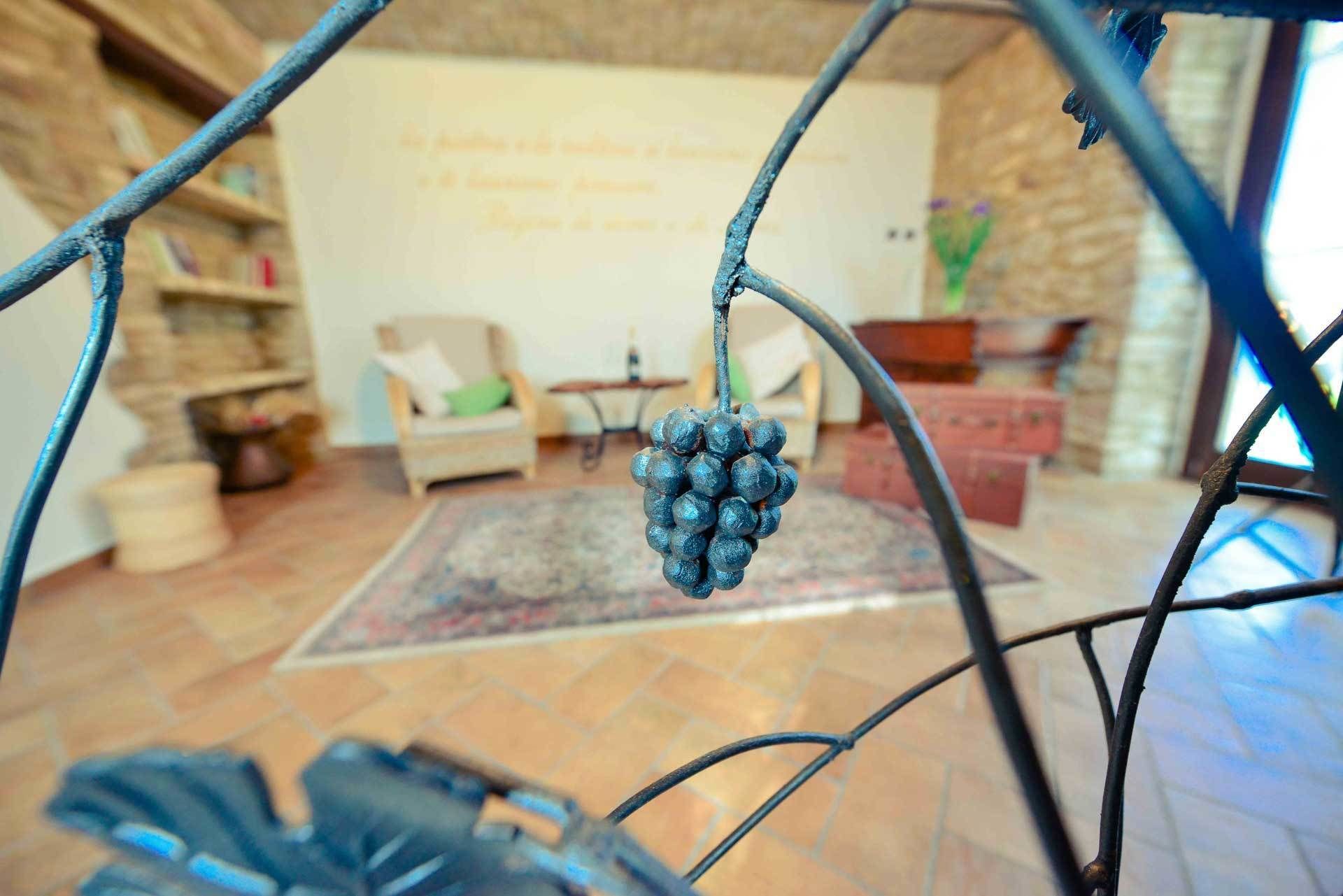 A room with a rustic stone wall, a wooden chair, a small table, and a hanging grapevine.
