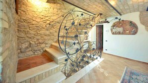Una escalera de piedra con barandillas de metal y un muro rústico.
