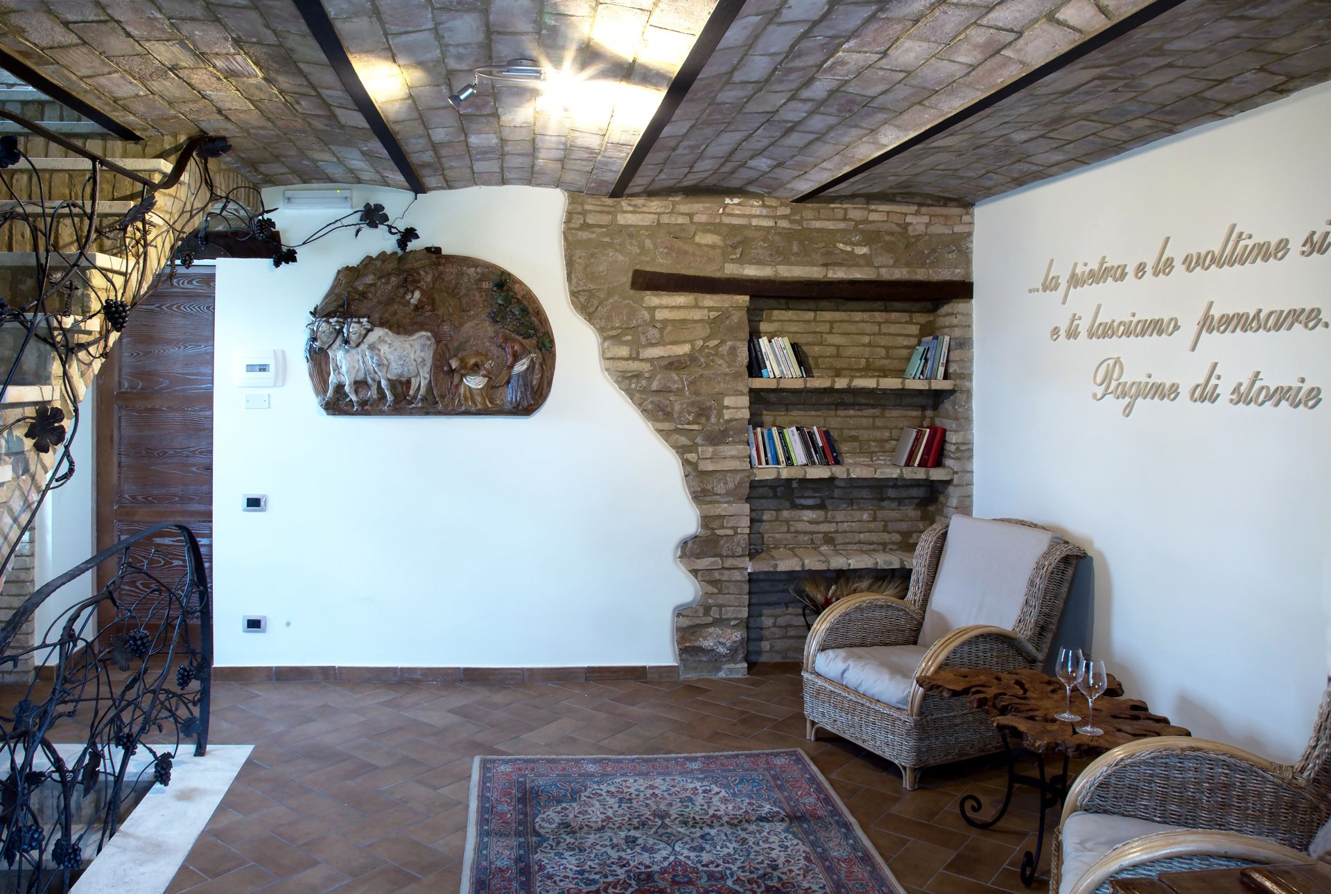 A cozy living room with a stone fireplace, wicker furniture, and a decorative wall piece.