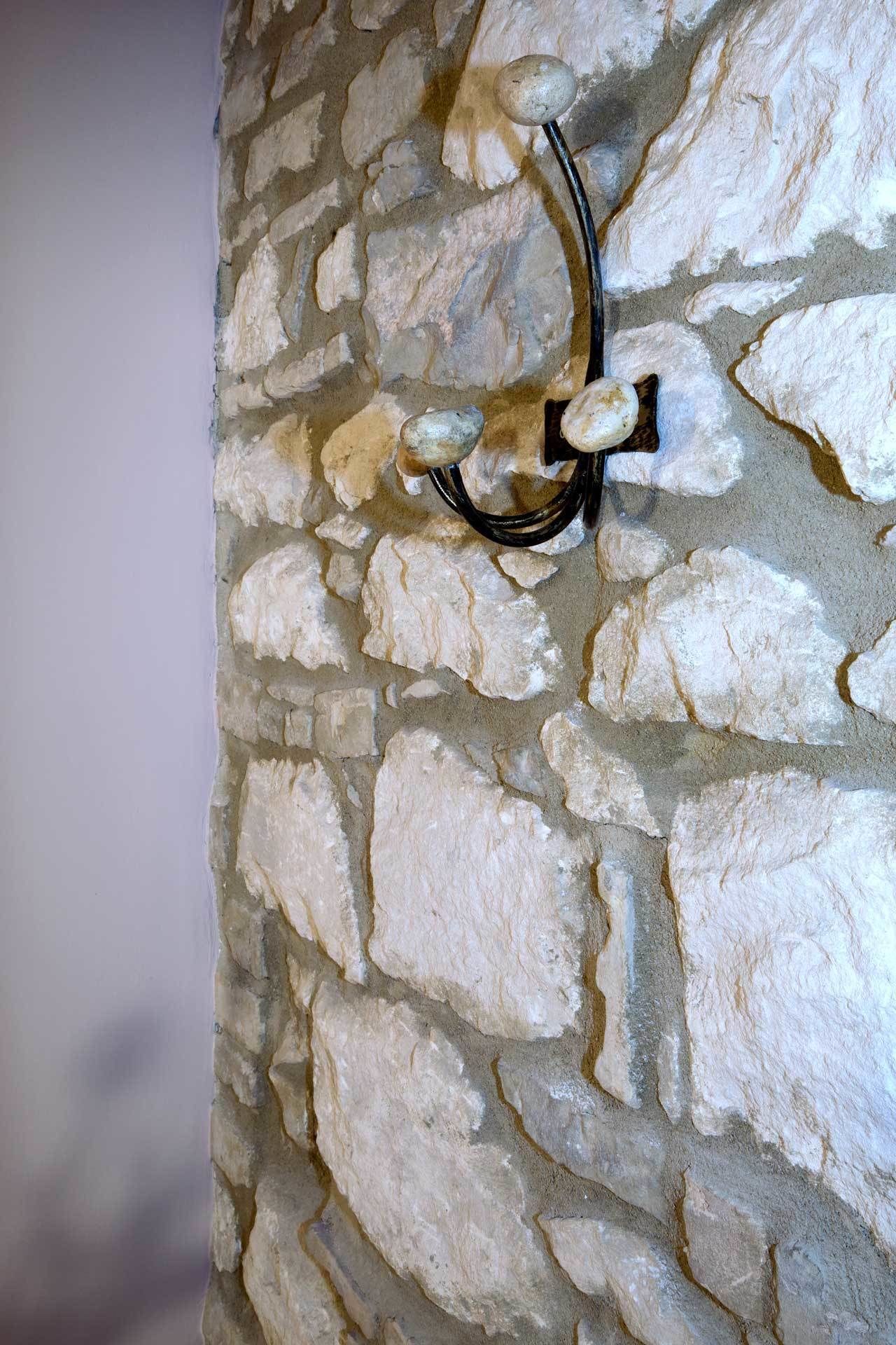 Un mur de pierres avec un crochet en métal.