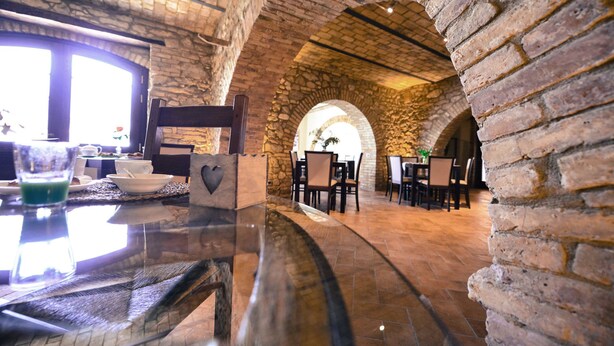 Un restaurante con arcos de piedra y paredes de ladrillo, con mesas y sillas dispuestas para comer.