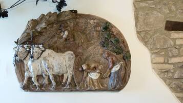 Escultura mural que representa una escena campestre con un hombre, una vaca y un perro.