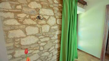 Una habitación con pared de piedra, cortina verde y piso de baldosas.