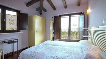 A bedroom with a bed, wardrobe, desk, and a window with a view.