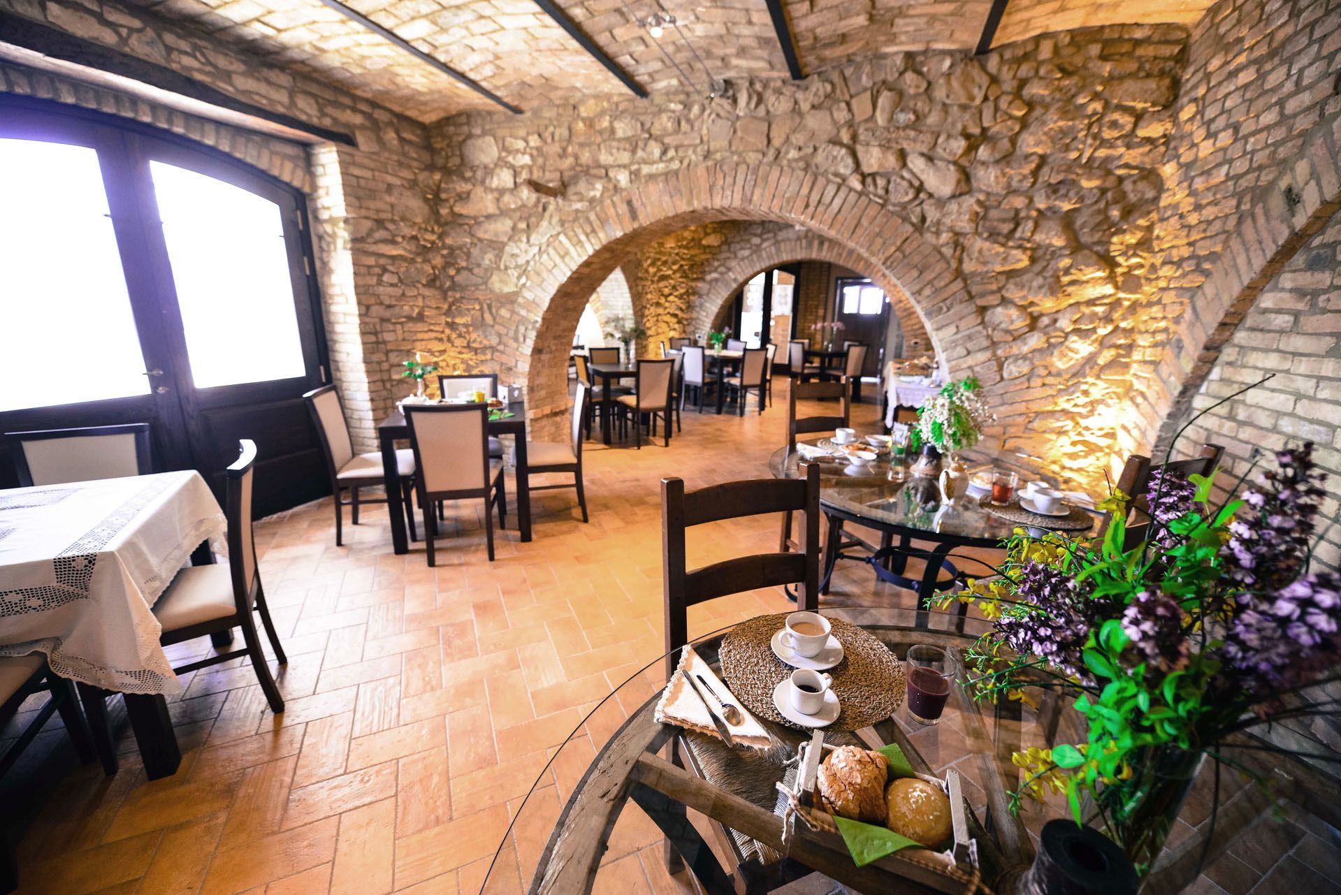 Un restaurante con arcos de piedra, mesas y sillas de madera.