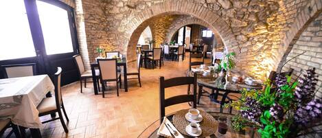 Un restaurante con arcos de piedra, mesas y sillas de madera.