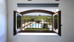 Una habitación con un amplio ventanal arqueado que da a una piscina y un viñedo.
