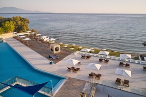 A rooftop pool area with lounge chairs and umbrellas, overlooking a body of water. - Cavo Orient Beach Hotel (Zakynthos)