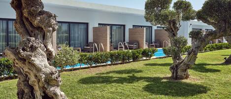 Et moderne hotel med swimmingpool, udendørs siddepladser og velplejede grønne områder.