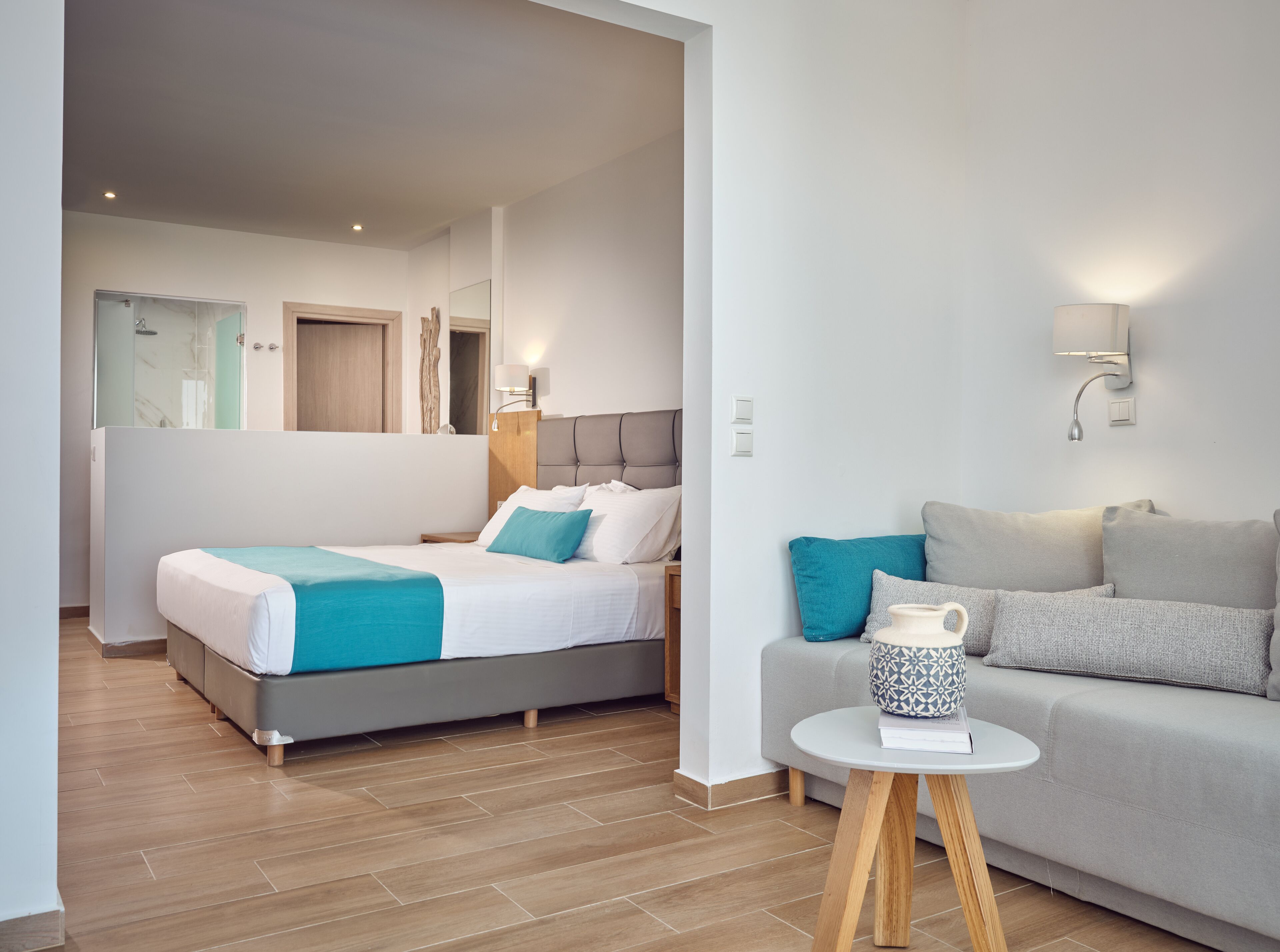 Et moderne hotelværelse med seng, sofa, et lille bord og badeværelse med bruser.
