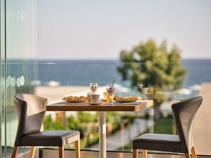 A table with breakfast items and a glass of orange juice, overlooking a scenic view of the sea and greenery. - Cavo Orient Beach Hotel (Zakynthos)