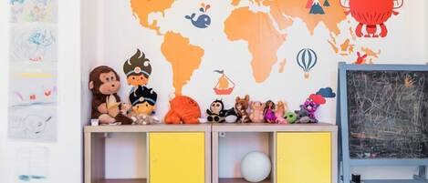 Kinderzimmer mit einer Weltkarte an der Wand, einem Regal voller Spielzeug und einer Kreidetafel.