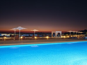 A poolside area with lounge chairs and umbrellas, a pool, and a sunset view. - Cavo Orient Beach Hotel (Zakynthos)
