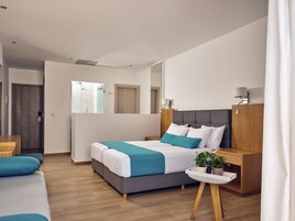 Una habitación de hotel moderna con una cama grande, mesitas de noche, un escritorio pequeño y un espejo.
