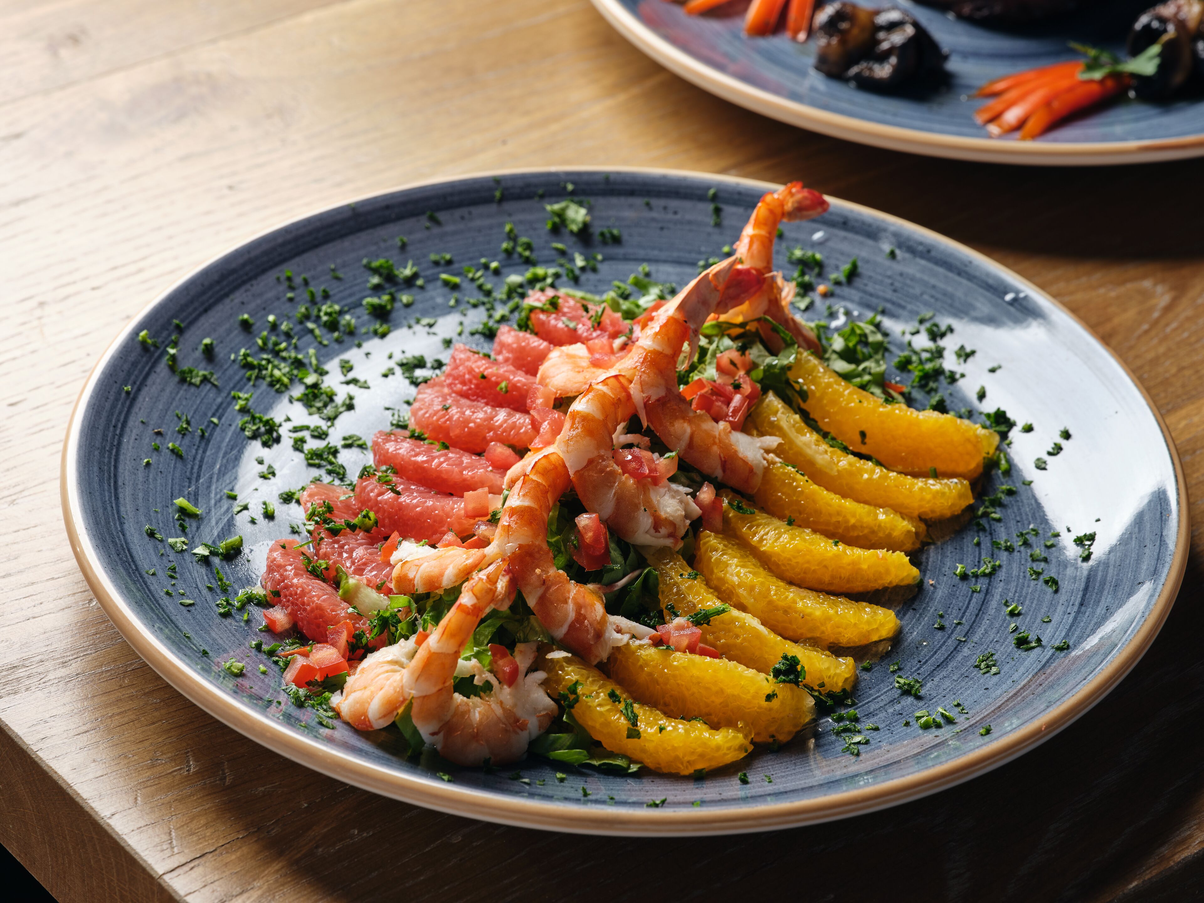 A plate of food with shrimp, citrus slices, and herbs.