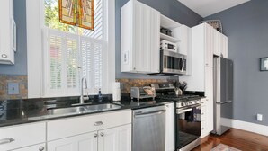 Una cocina moderna con armarios blancos, electrodomésticos de acero inoxidable, lavavajillas y estufa.