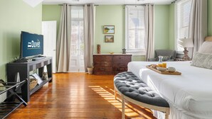 Un dormitorio con cama, televisor, cómoda y ventana con cortinas.