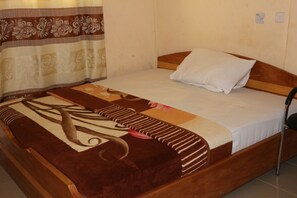 A single bed with a wooden headboard, a white pillow, and a brown and beige patterned blanket. - Nagino Lodge (Nyanyanu)