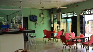 A dining area with red chairs and a table, a bar area with stools, and a television mounted on the wall. - Nagino Lodge (Nyanyanu)