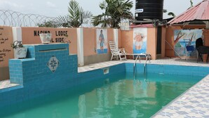 A swimming pool with a blue tiled edge, a lounge chair, and a mural on the wall. - Nagino Lodge (Nyanyanu)
