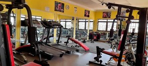 Un gimnasio con cintas de correr, máquinas de pesas y bancos.