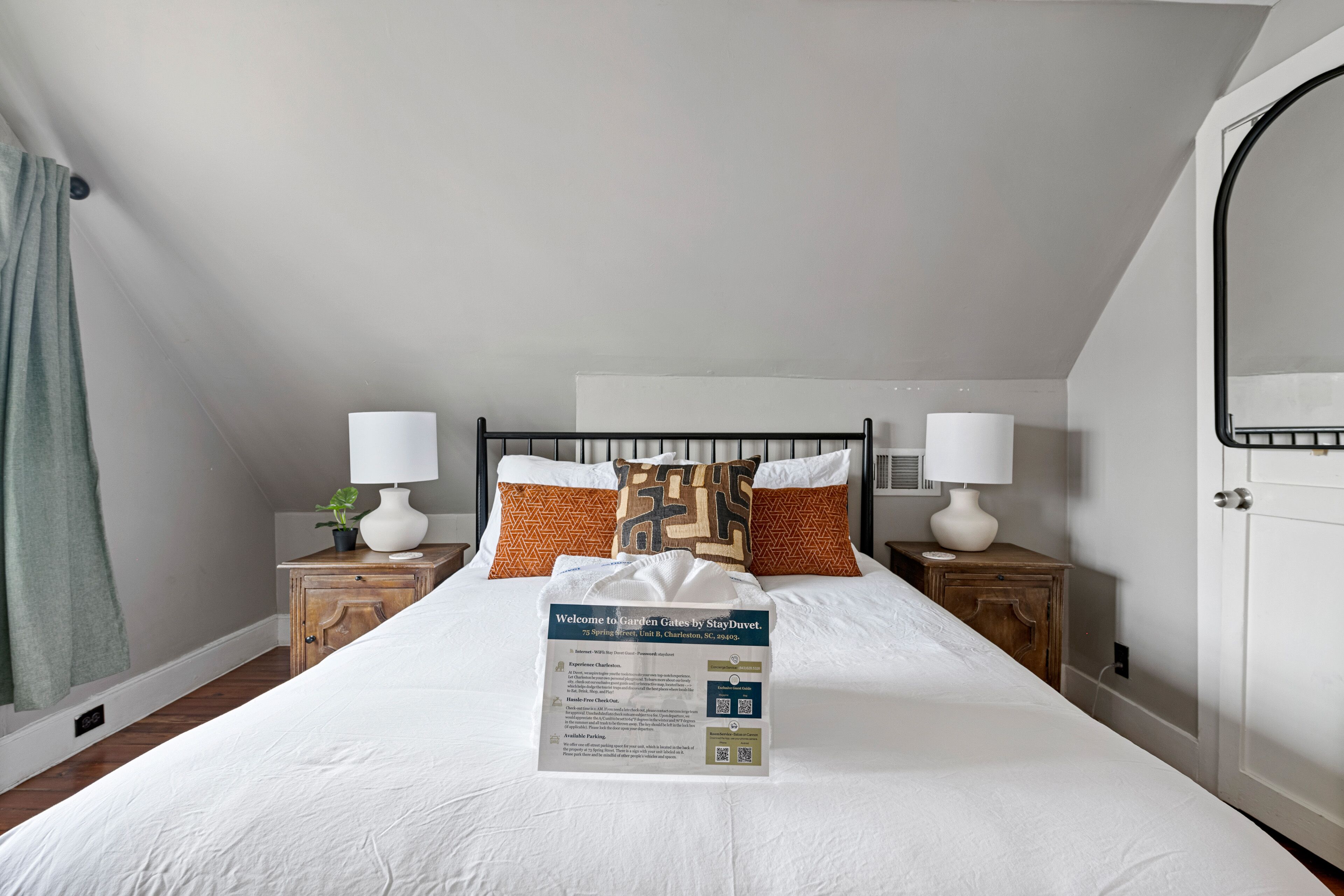 A neatly made bed with a welcome sign, two bedside tables with lamps, and patterned pillows.
