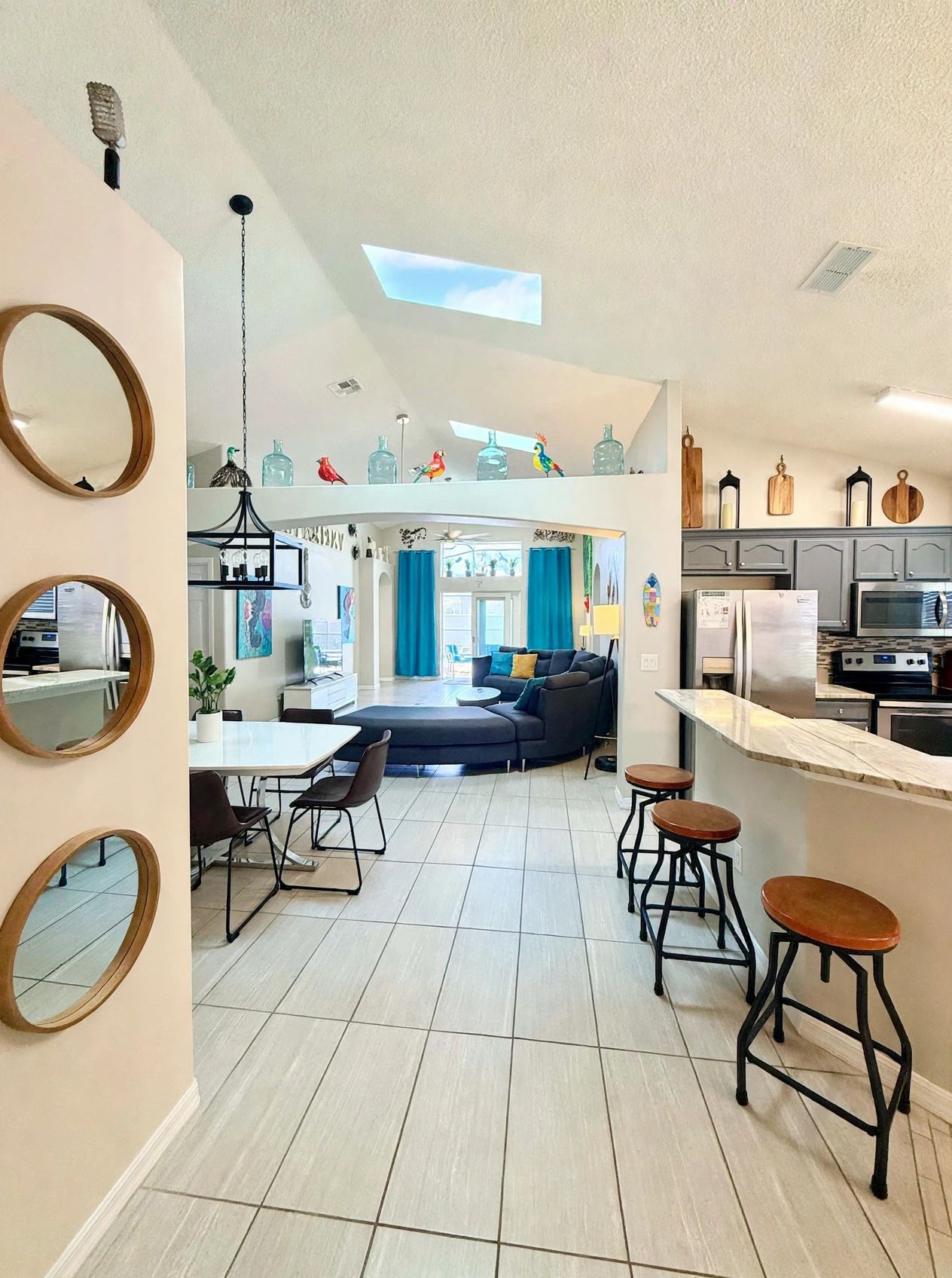 A modern kitchen with a central island, bar stools, and a dining area with a table and chairs.