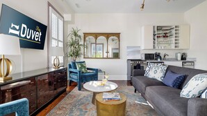 A modern living room with a sofa, armchairs, a coffee table, and a TV mounted on the wall.