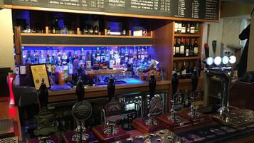 Un bar con diversas botellas de licores y una selección de cervezas en grifo.