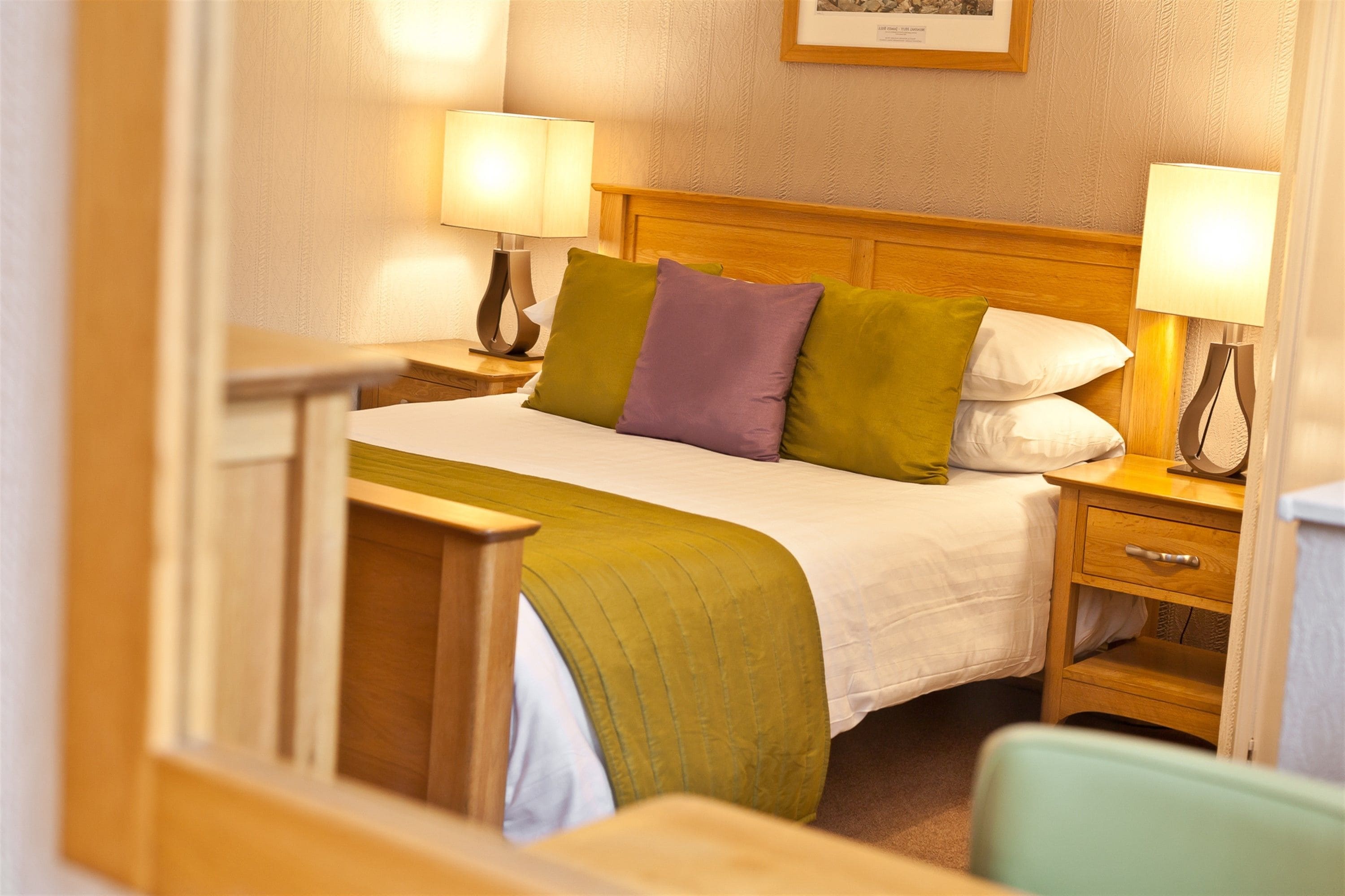 A hotel room with a bed, two bedside tables, a nightstand, a chair, and a lamp on each table.