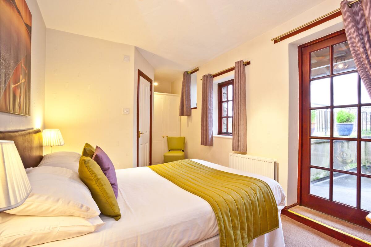 A bedroom with a bed, a chair, a window, and a door.