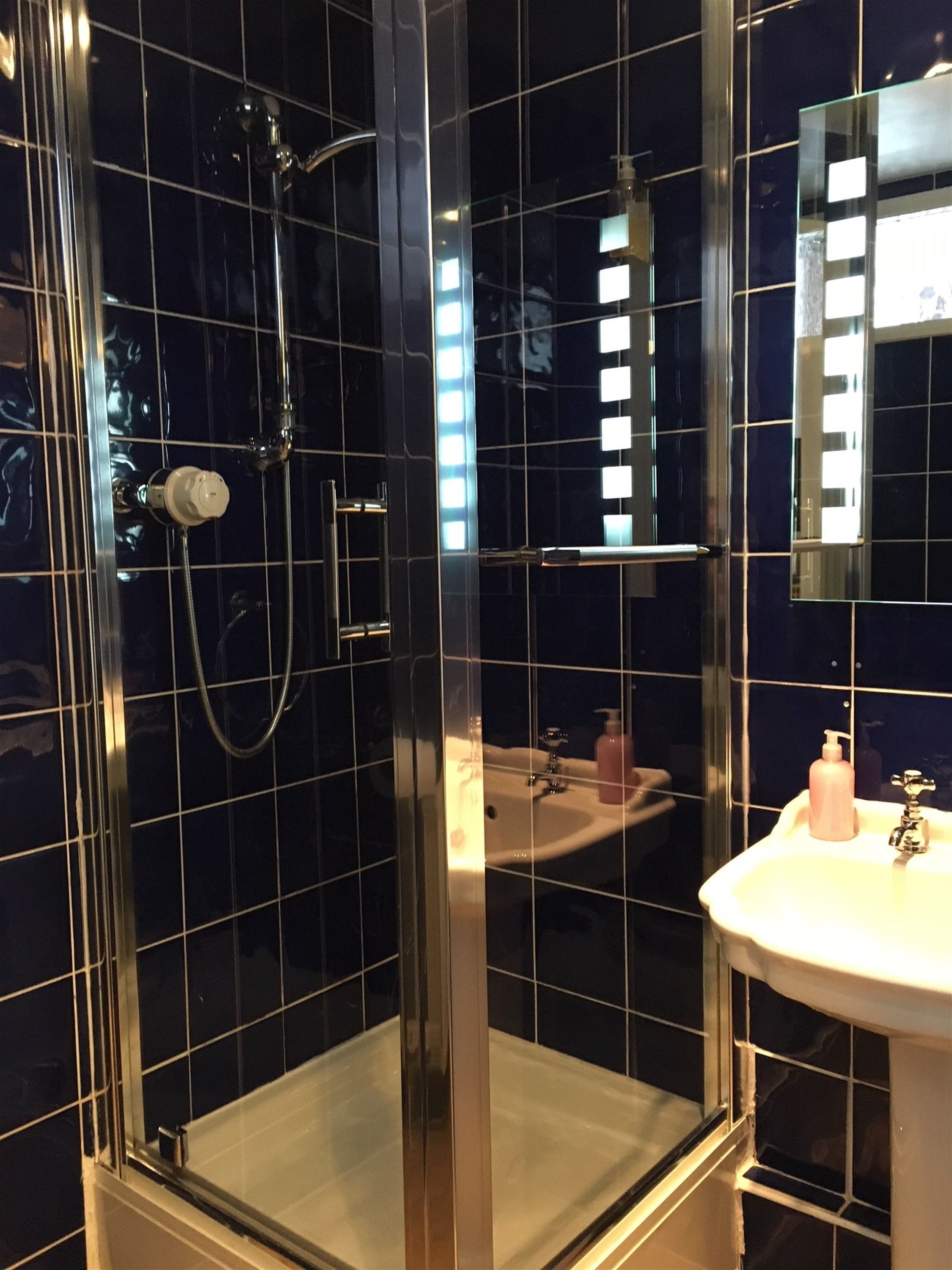 A modern bathroom with a glass-enclosed shower, a white sink, and a mirror reflecting the room.