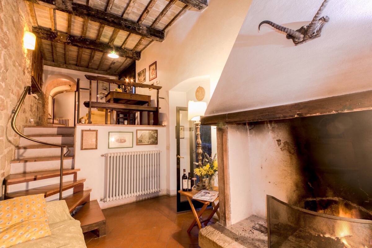 A cozy room with a fireplace, wooden staircase, and a radiator.