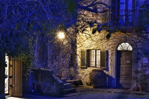 A stone building with a rustic charm, featuring a wooden door, a bench, and a large barrel. - Pieve di Caminino Historic Farm (Roccastrada)