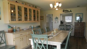 A kitchen with a wooden table, teal chairs, and a chandelier. - FALL RATES ! Discounted rates. Book with Affirm. New Beach! (Dauphin Island)