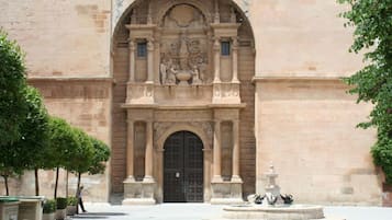 A historic building with an ornate entrance, a fountain, and a paved courtyard.