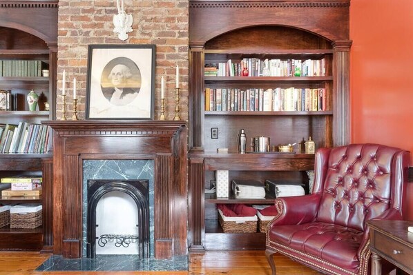 A library with bookshelves, a fireplace, and a leather armchair.