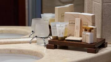 A bathroom vanity with a marble countertop, a glass shower enclosure, and toiletries including a soap dispenser, a toothbrush holder, and a soap bar.