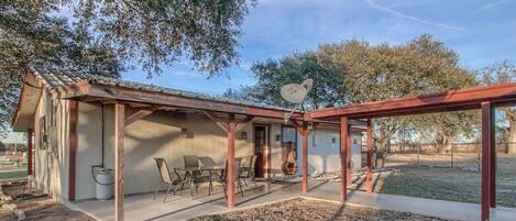 A single-story building with a covered patio area, a gas tank, and outdoor seating.