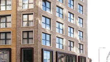 A multi-story building with a brick facade, large windows, and a ground-level entrance with glass doors.