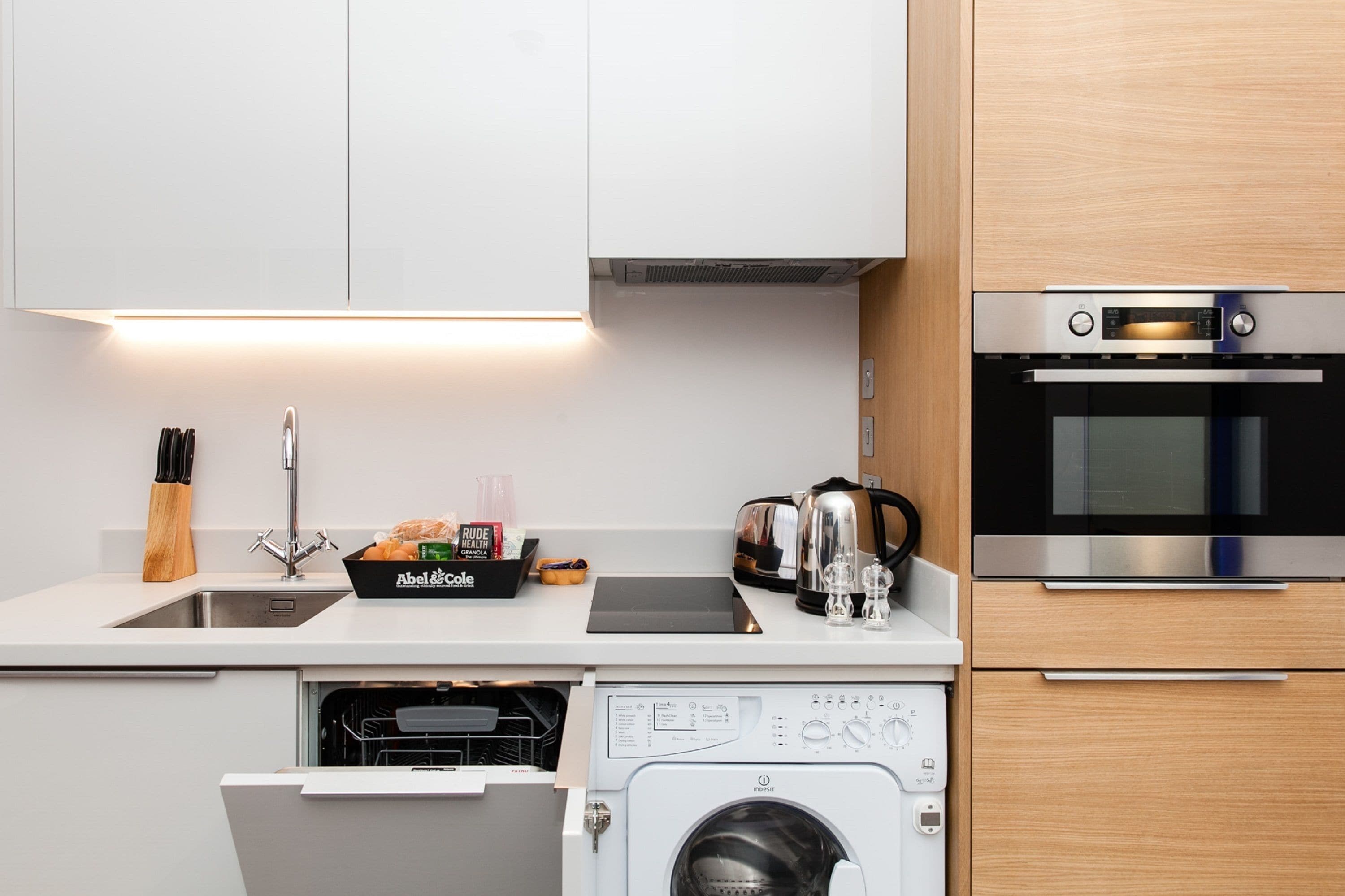 A modern kitchen with white cabinets, a stainless steel oven, a dishwasher, and a coffee maker.