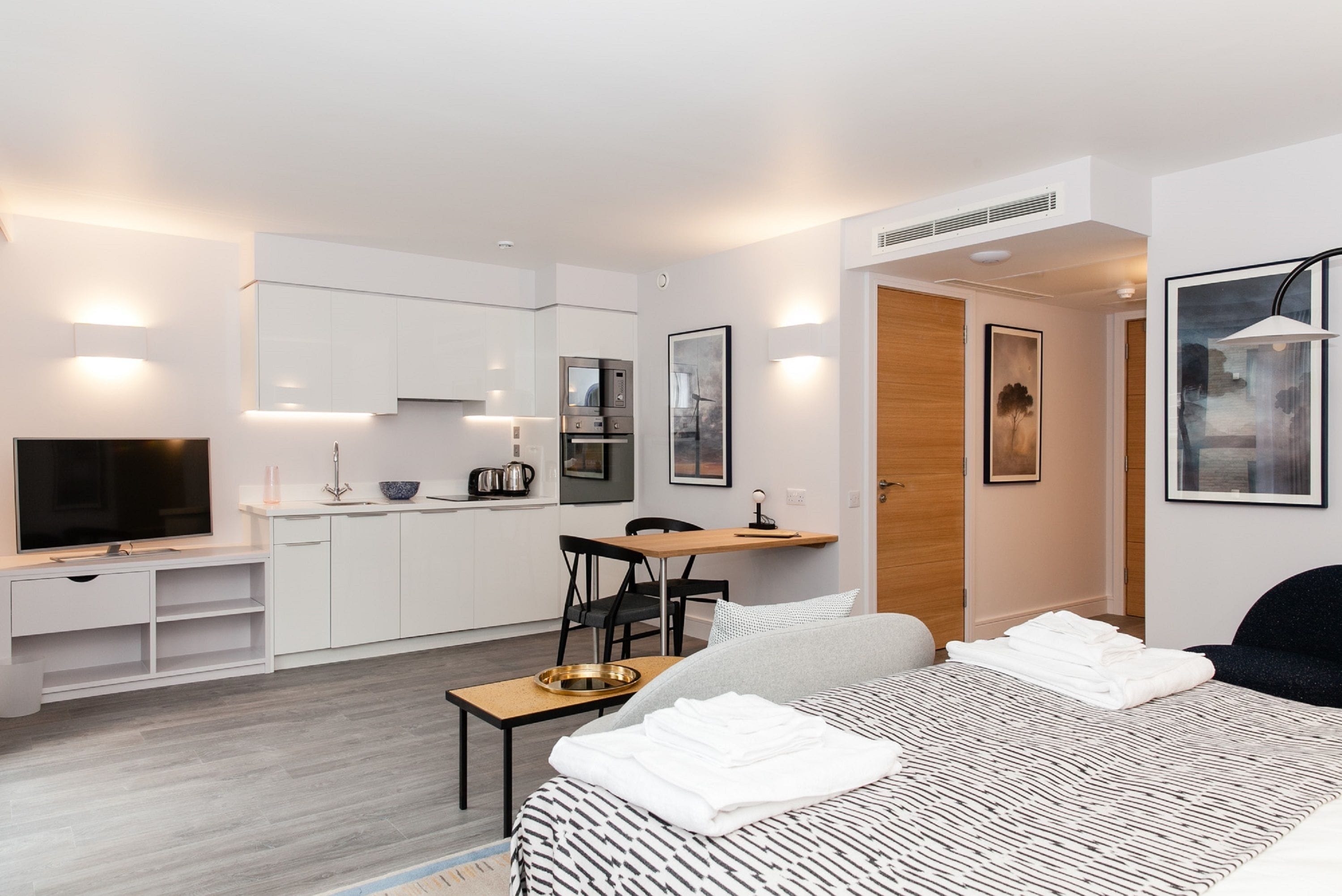 Una habitación de hotel moderna con cama, escritorio, televisión y kitchenette.
