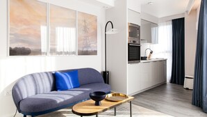A modern living room with a sofa, a coffee table, and a kitchen area with appliances.