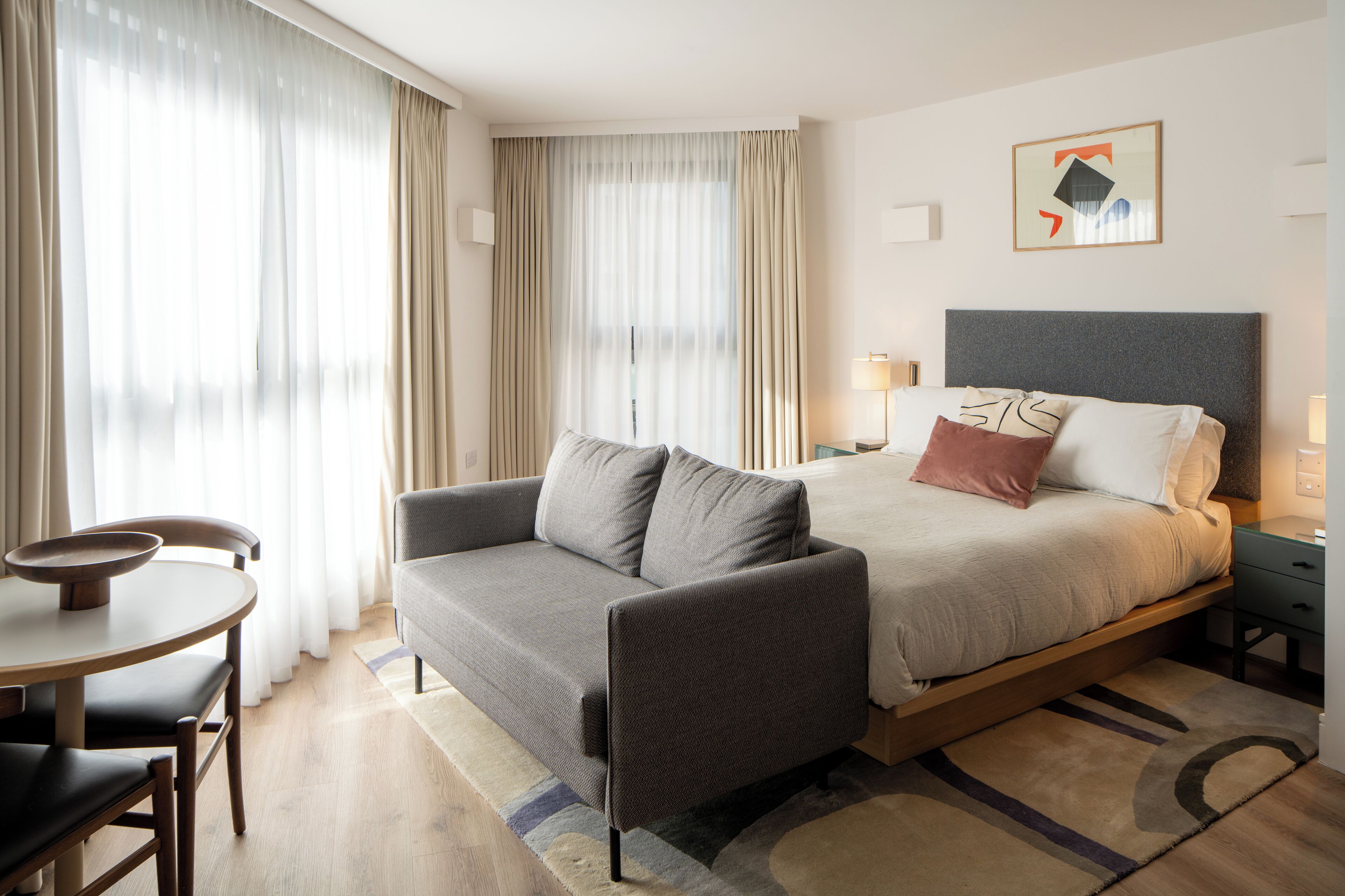 A hotel room with a bed, a sofa, a small table, and a chair.